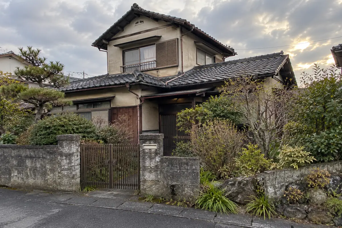 公道側から見た瓦屋根と庭木のある古い日本家屋