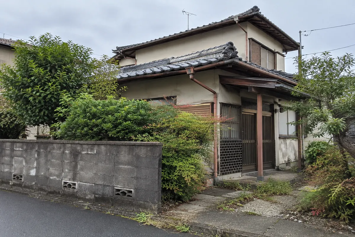 道路から見た古い日本の家と庭木、外壁を描いた説明用生成写真