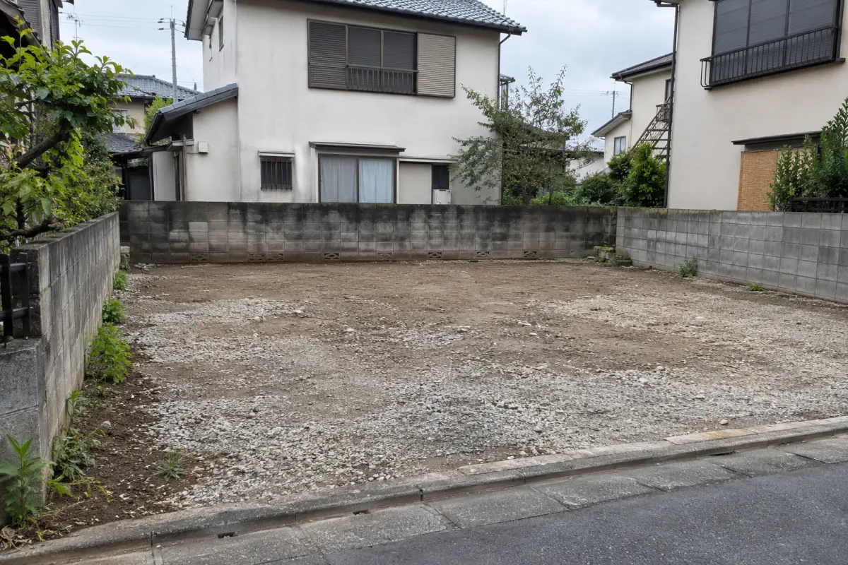 住宅に囲まれた小さな更地を道路側から見た説明用の生成写真
