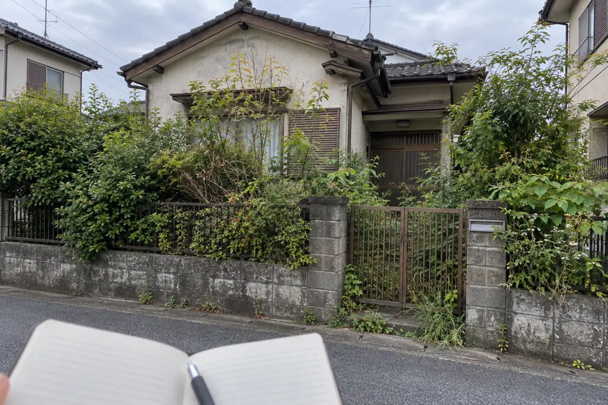 道路側から見た庭木の伸びた古い日本の家と観察用のノートを描いた生成写真