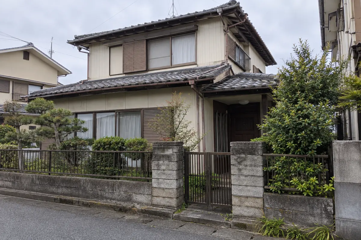 門と庭木、屋根と外壁が見える古い日本の戸建て住宅の説明用生成写真