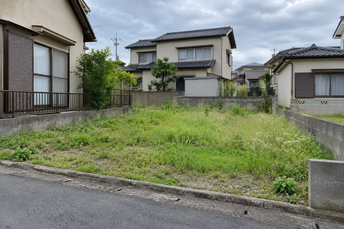住宅の間に残る草の生えた小さな空き地を描いた説明用生成写真