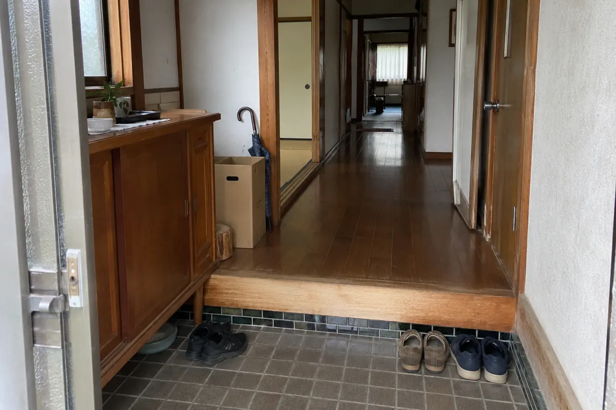 靴と傘が置かれた古い家の玄関から廊下を見た説明用画像