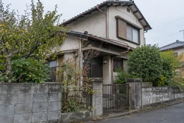 道路側から見た古い日本の家の門、庭木と外壁を描いた説明用の生成画像